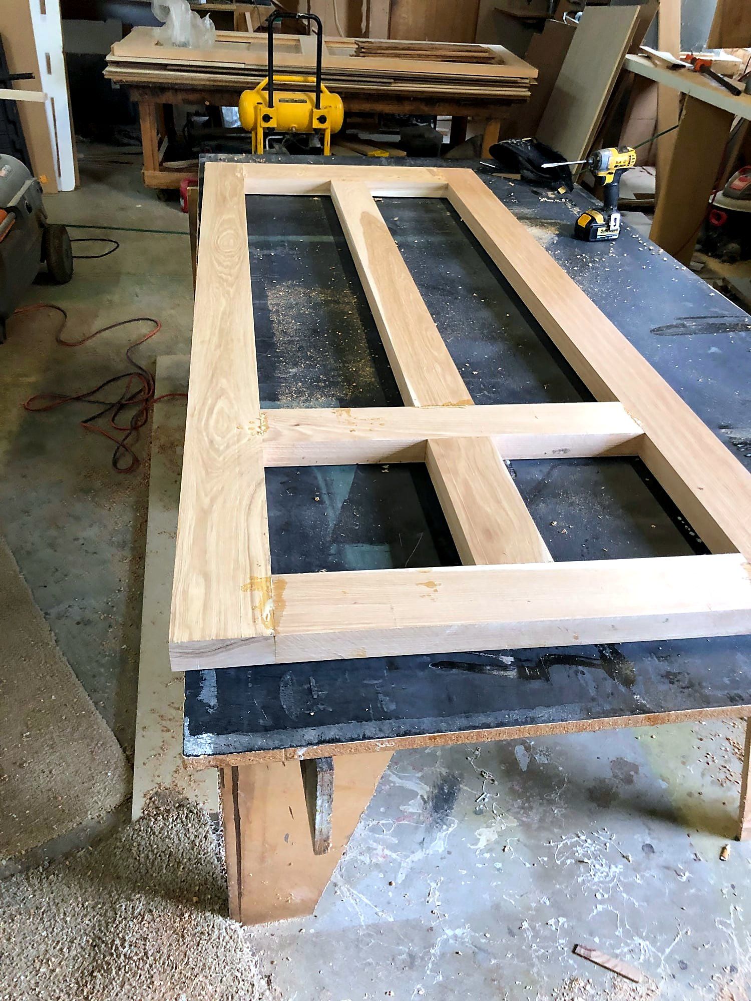 Four-lite door sash under construction on a shop bench, mortised pine rails and stiles glued up around the empty glass openings