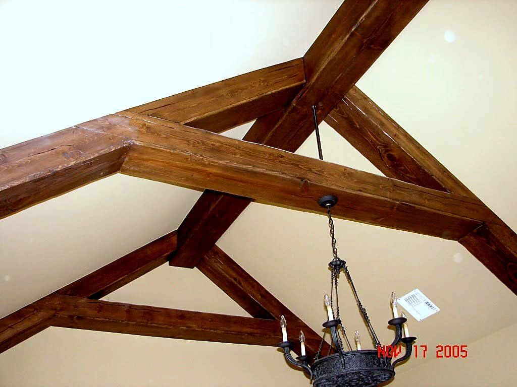 Exposed wood king-post truss ceiling with a wrought iron candle chandelier